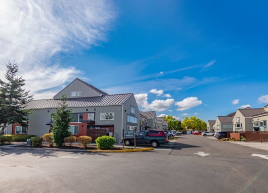 a parking lot in front of houses with a blue sky