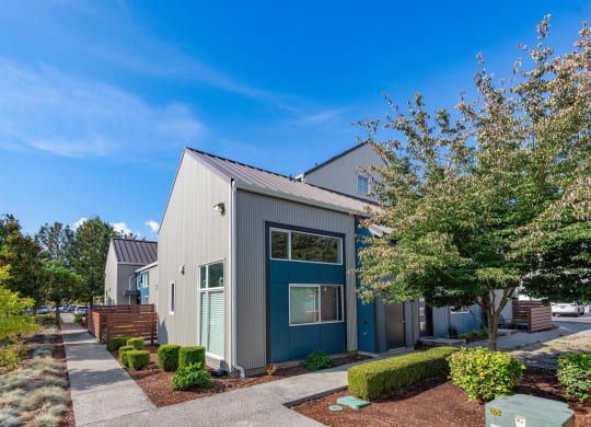 a gray and blue house with trees and a sidewalk