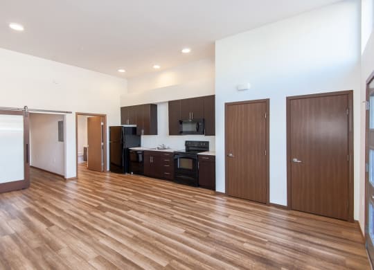 an empty living room with wood flooring and a kitchen