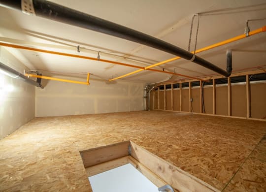a large room with wood flooring and pipes in it