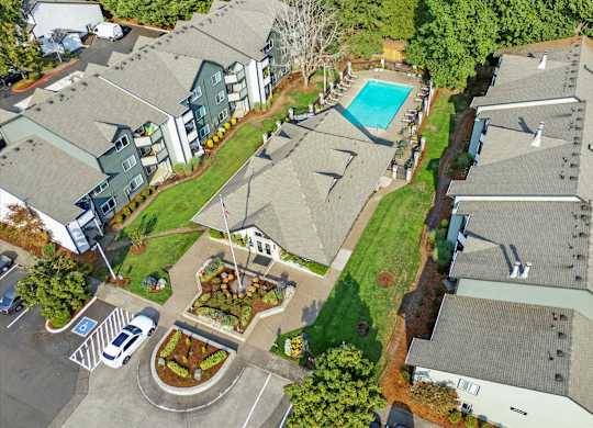 A bird's eye view of a residential area with houses, a pool, and a parking lot.