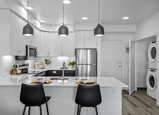 an open kitchen with a counter and two black chairs