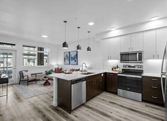 an open kitchen and living room with white cabinets and stainless steel appliances