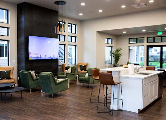 A modern living room with a television, comfortable seating, and a kitchen area.