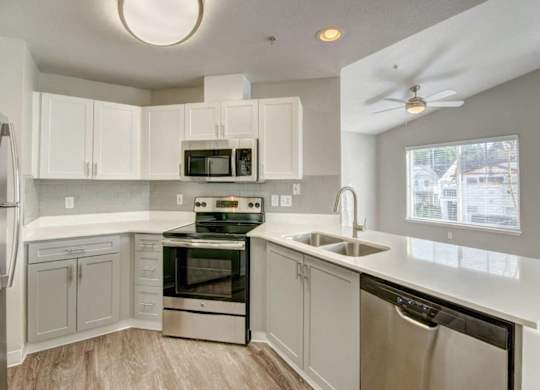 Modern Kitchen With Stainless Steel Appliance Suite, Spacious White Cabinetry, and Sleek Counters at Clock Tower Village, Washington, 98327