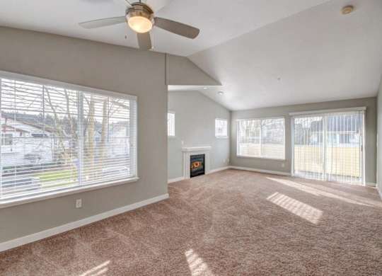 Living Room with Fireplace, Ceiling Fan, Plush Carpet, and Expansive Windows at Clock Tower Village, Washington, 98327