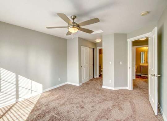 Spacious Unfurnished Bedroom With a Ceiling Fan, Carpet Flooring, and Natural Light From the Window at Clock Tower Village, DuPont Washington