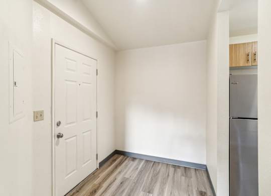 A white door is in a room with a wooden floor.