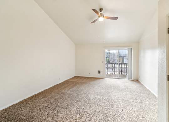 A room with a ceiling fan and carpeted floor.