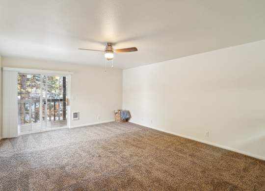A room with a ceiling fan and carpeted floor.