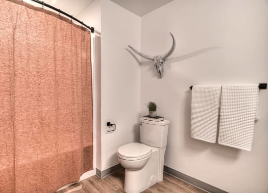 a bathroom with a toilet and a shower curtain and a deer skull on the wall
