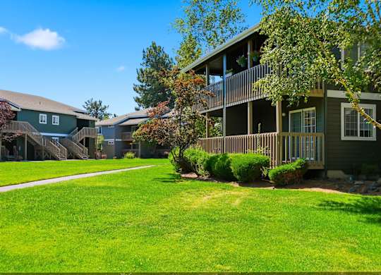 A green lawn in front of a building with a balcony.