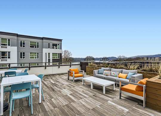 A wooden deck with a white table and blue chairs.