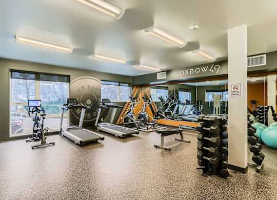 A gym with a variety of equipment including treadmills, exercise bikes, and weight racks.