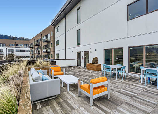 A patio with a table and chairs is surrounded by a grassy area.