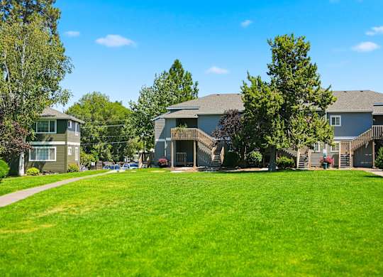 A large grassy area in front of a building with trees.
