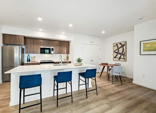 A kitchen with a white island and blue chairs.
