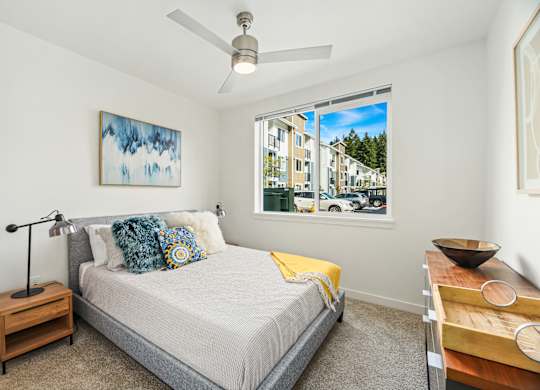 A bedroom with a bed, nightstand, and a painting on the wall.
