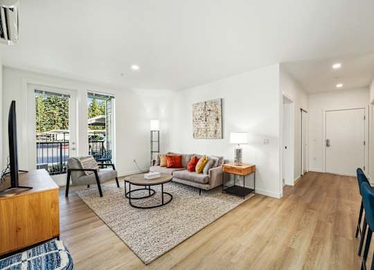 A living room with a couch, chairs, and a rug.
