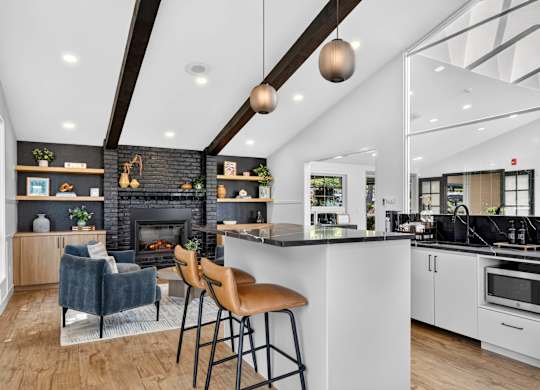 A modern kitchen with a fireplace and bar stools.