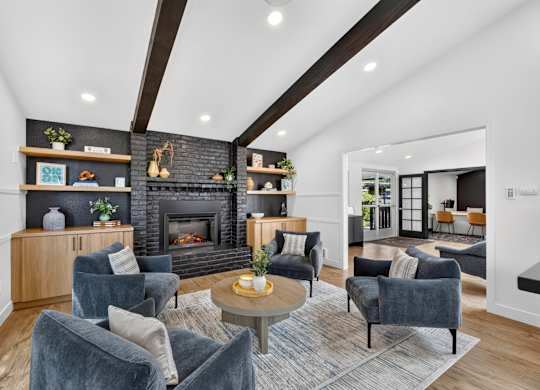 A living room with a fireplace and a grey rug.