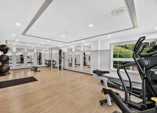 A spacious gym with wooden floors and a variety of exercise equipment.