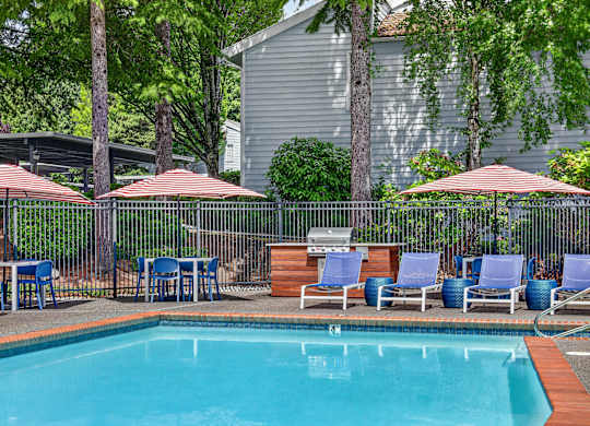 A pool surrounded by chairs and umbrellas.