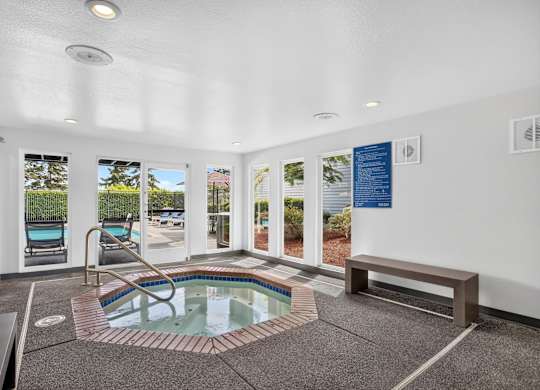 A small indoor pool with a hot tub in the middle of the room.