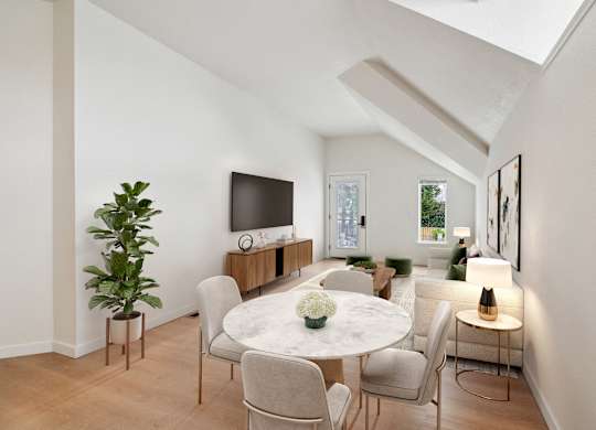 A white dining table with chairs and a television on a wooden cabinet.