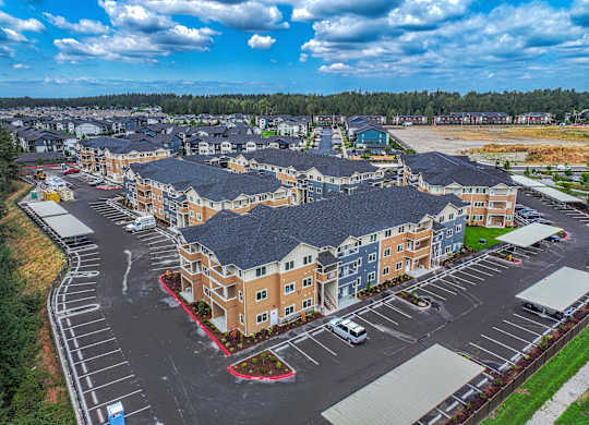 A large, multi-story residential building with a parking lot in front.