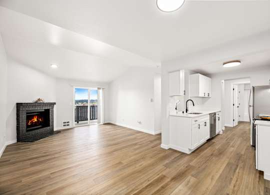 a living room with a fireplace and a kitchen with white cabinets