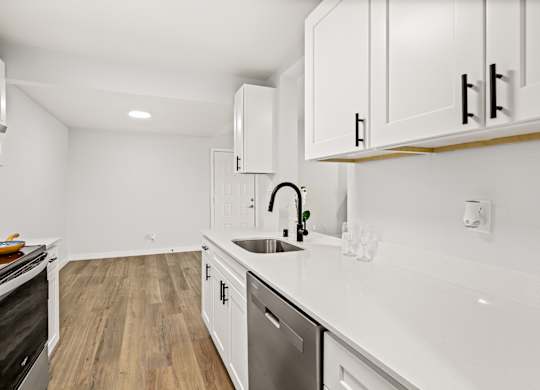 a renovated kitchen with white cabinets and white counter tops and a sink