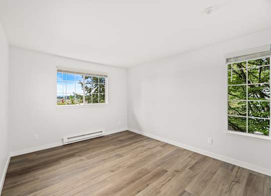 an empty room with white walls and wood floors and a window