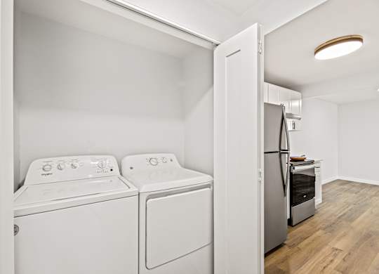 a white washer and dryer in a room with a door to a kitchen