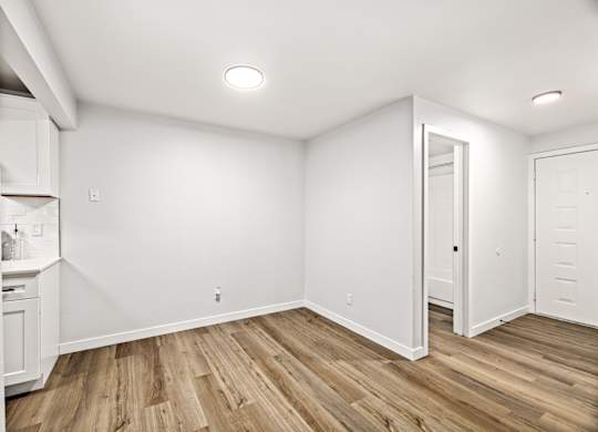 the living room and kitchen of a new home with white walls and wood flooring