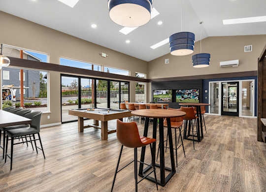 A room with a long table surrounded by chairs and a bar area.