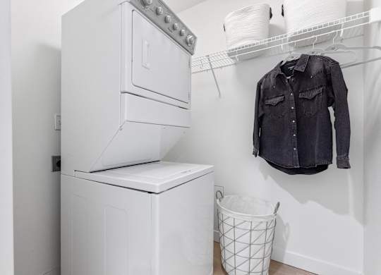 A black shirt hanging on a white wall next to a washing machine.