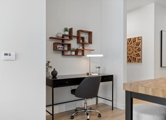 A modern home office with a black desk and a black chair.