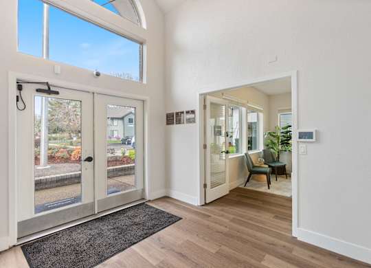A white interior with a black rug and a glass door.