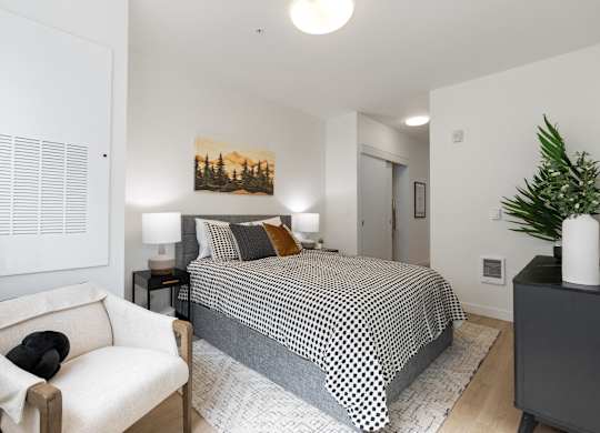 A bedroom with a bed, a chair, and a painting on the wall.