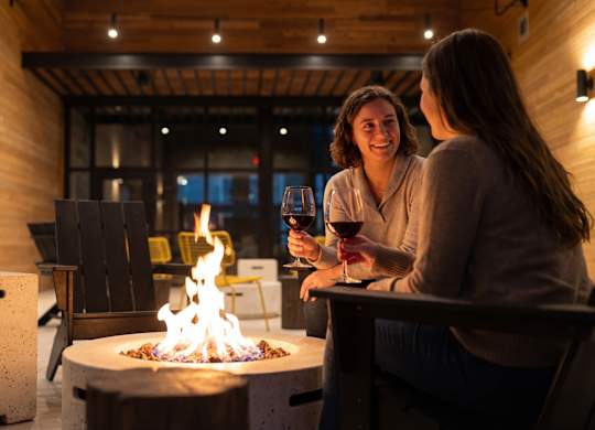 Two women sitting by a fire pit at night.