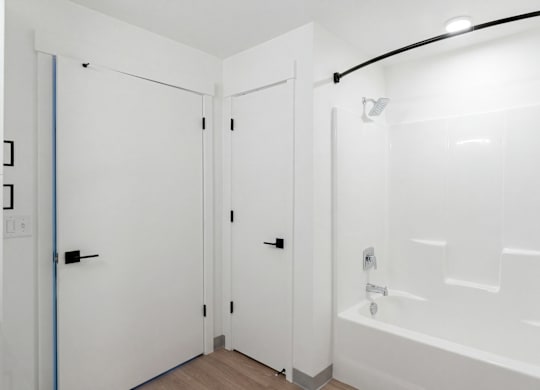 A white bathroom with a tub and two doors.
