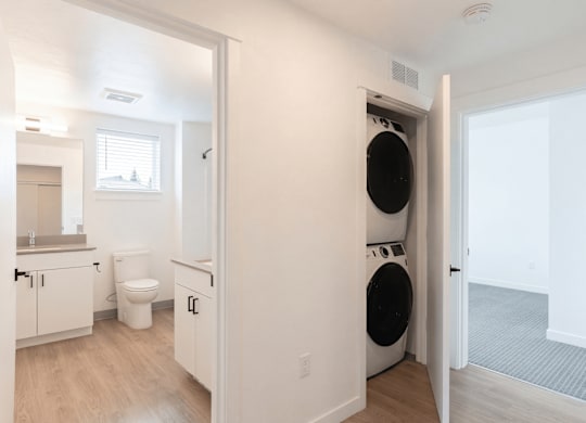 A white bathroom with a toilet, sink, and washer and dryer.