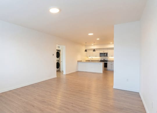 A spacious room with a kitchen area in the background.