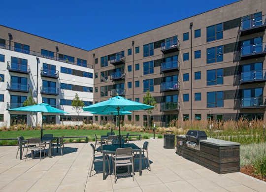 A patio area with tables and chairs is surrounded by apartment buildings.