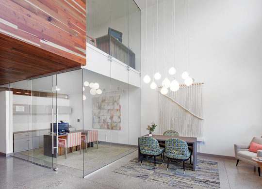A modern living room with a glass wall separating it from a wooden deck.
