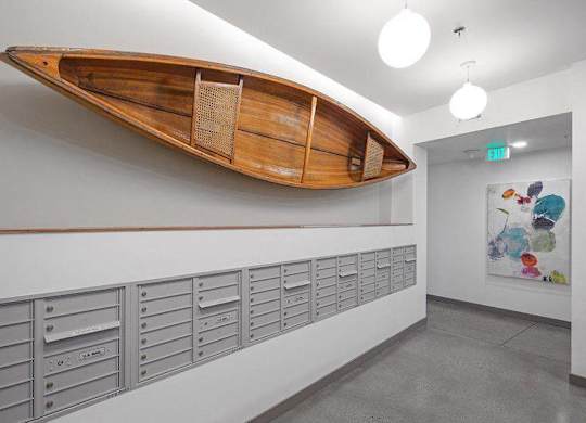 A wooden boat mounted on a wall above a row of mailboxes.