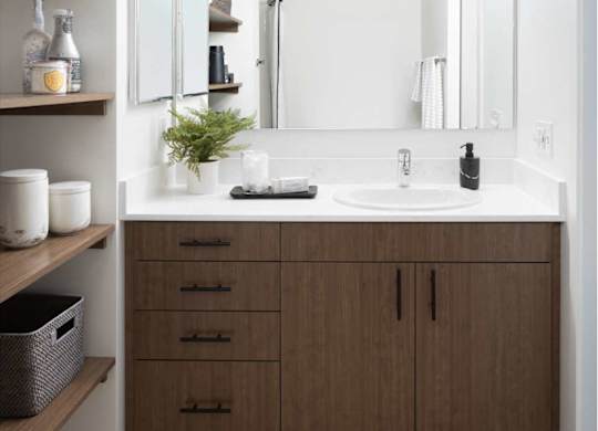 A bathroom with a white sink and brown cabinets.