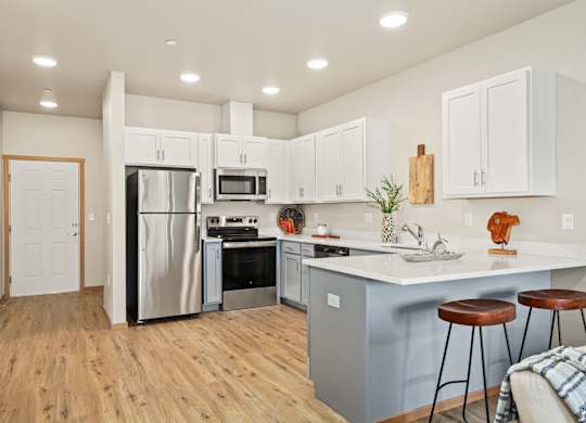 A kitchen with white cabinets and a wooden floor.