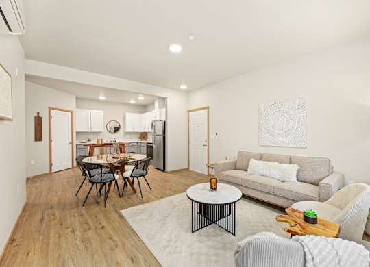 A modern living room with a dining table and grey couch.